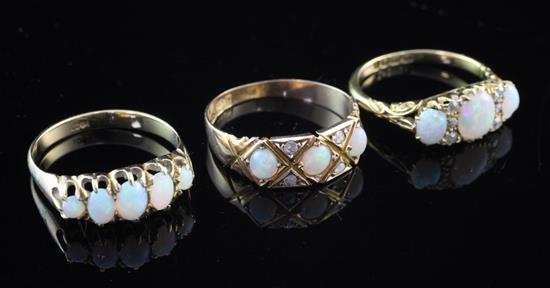 Three early 20th century gold and white opal rings, various sizes.